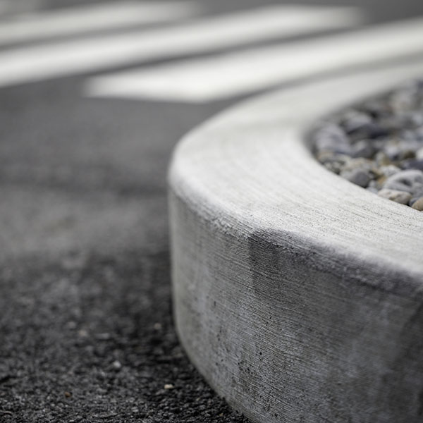 A curb with an asphalt road and a rock garden on the sides