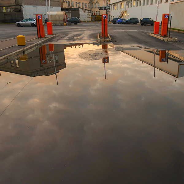 a large puddle on the asphalt after the rain with the reflected evening sky and clouds