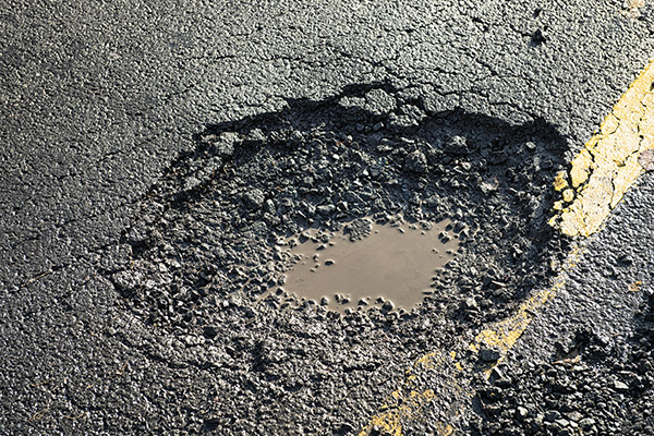 Close-up of the effects of road weathering and neglect - a deep pot hole causing a danger to drivers.