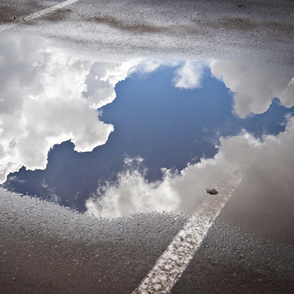 Puddle with sky and clouds, parking lot after storm, California.